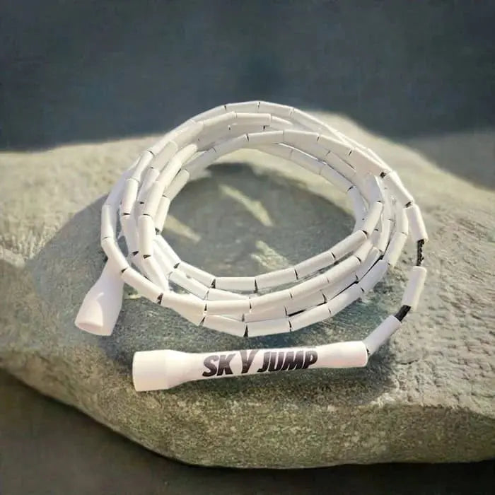 Corde à sauter perlée blanche posée sur un rocher gris, idéale pour vos entraînements.