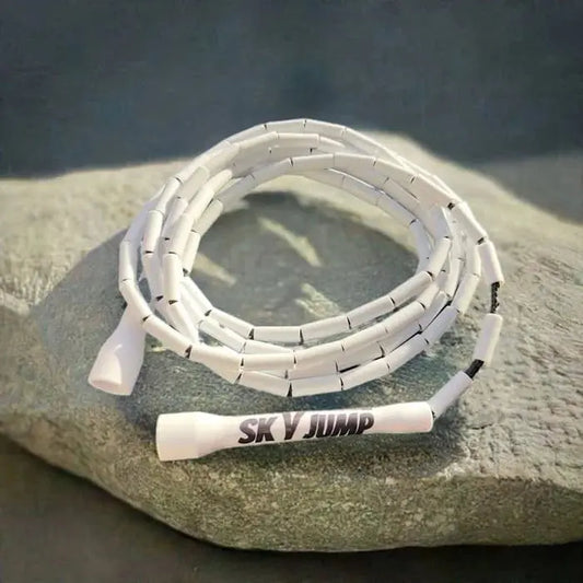 Corde à sauter perlée blanche posée sur un rocher gris, idéale pour vos entraînements.