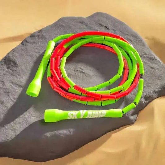 Image d'une corde à sauter perlée SkyJump aux couleurs du Maroc, posée sur un rocher dans le désert, avec un fond naturel