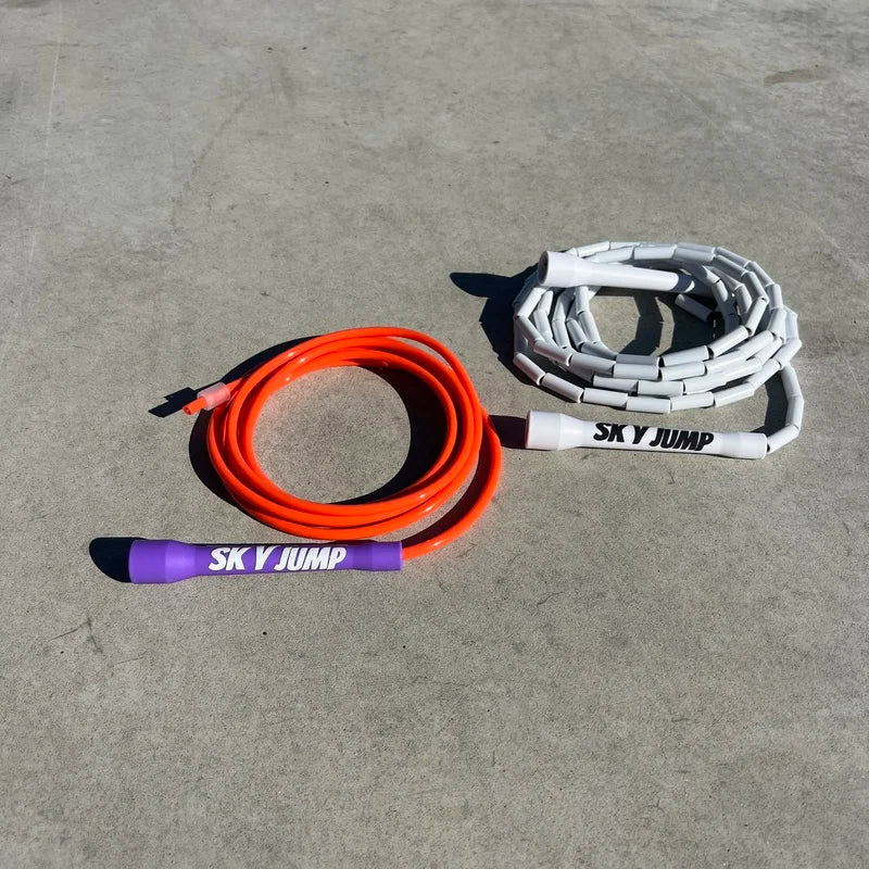 Corde perlée blanche Skyjump avec poignées blanches et corde PVC orange Skyjump avec poignées mauves.