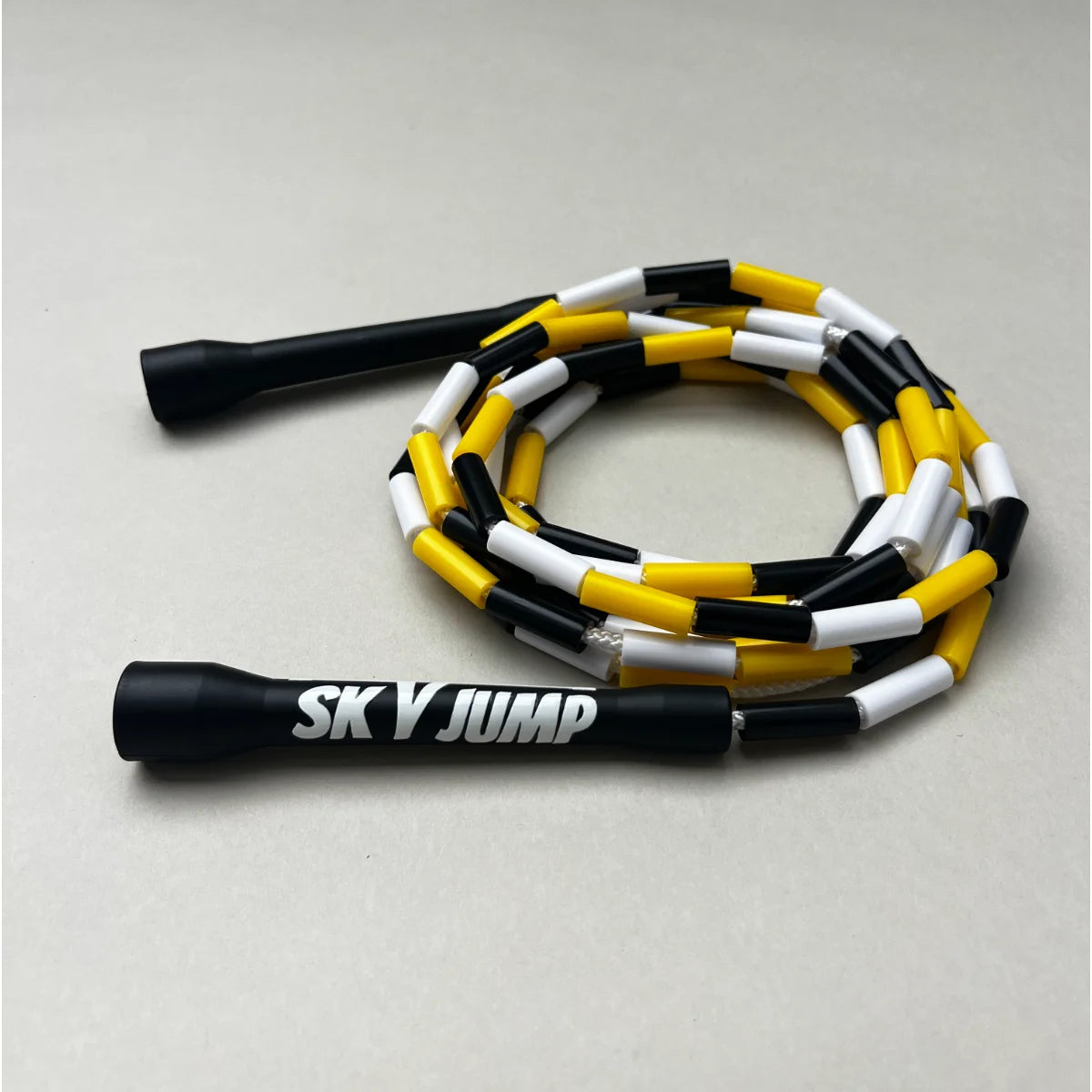Corde à sauter perlée Sky Fusion noire, jaune et blanche avec poignées noires.