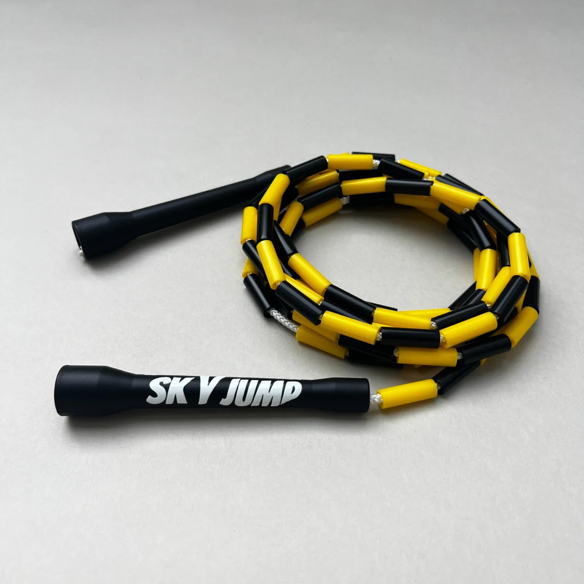 Corde à sauter perlée Sky Bumble noire et jaune avec poignées noires.