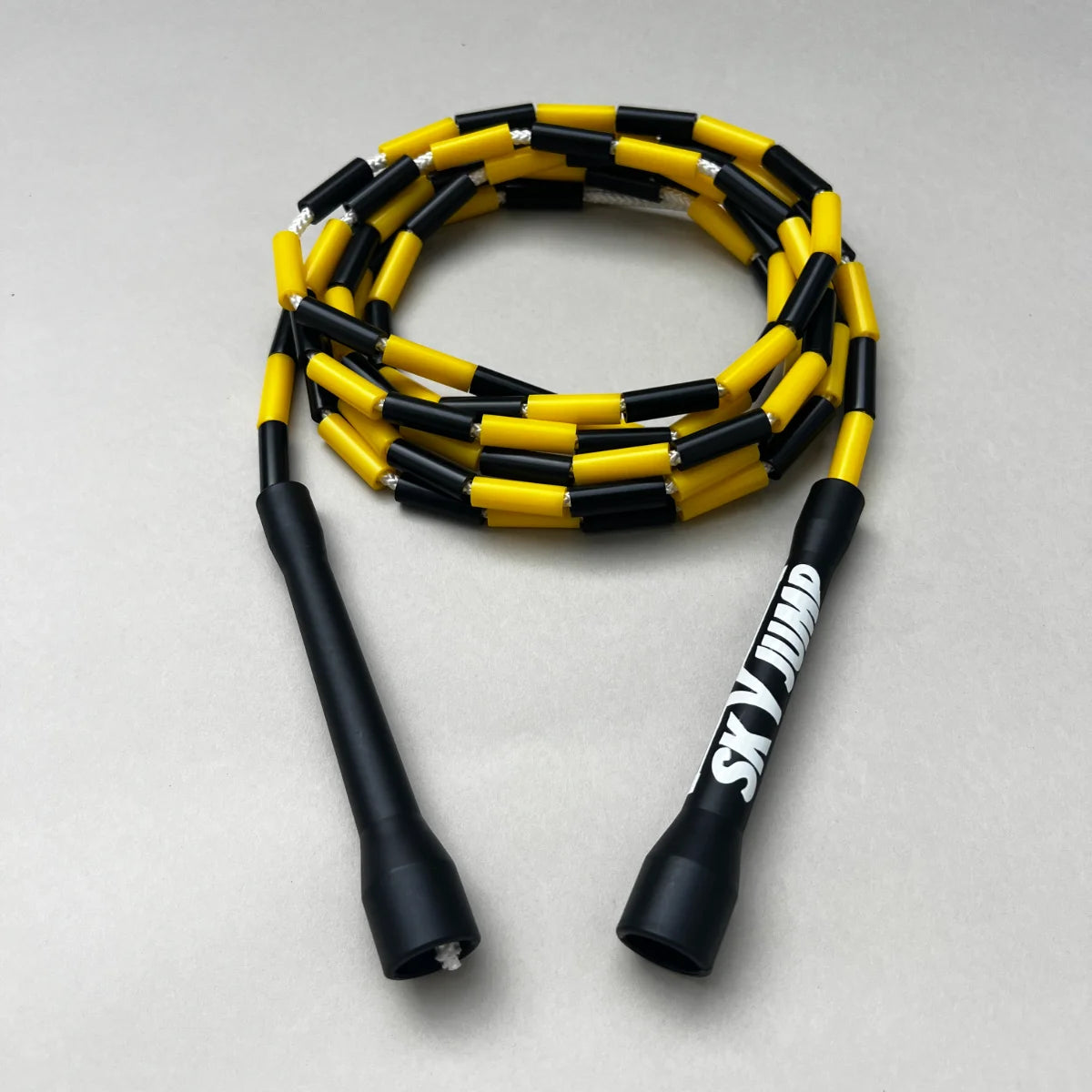 Corde à sauter perlée Sky Bumble enroulée avec poignées ergonomiques noires.
